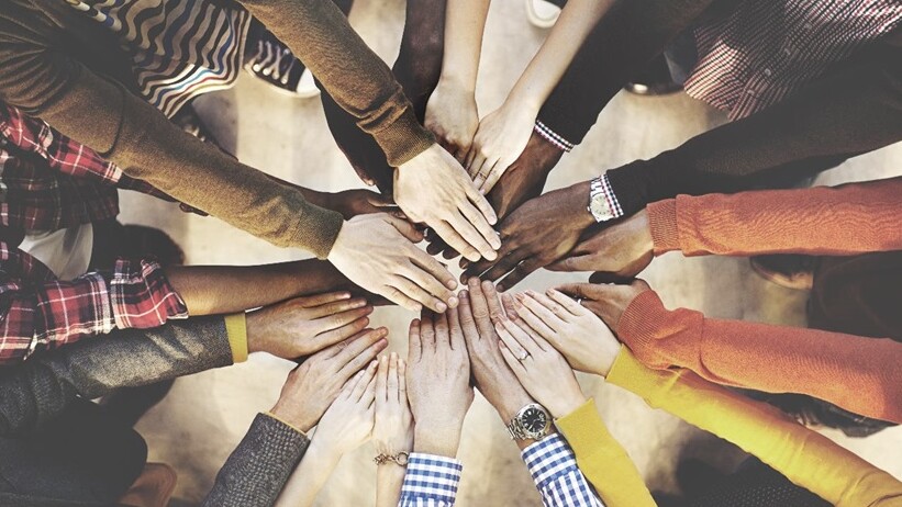 Team hand gesture with many hands of different skin colors