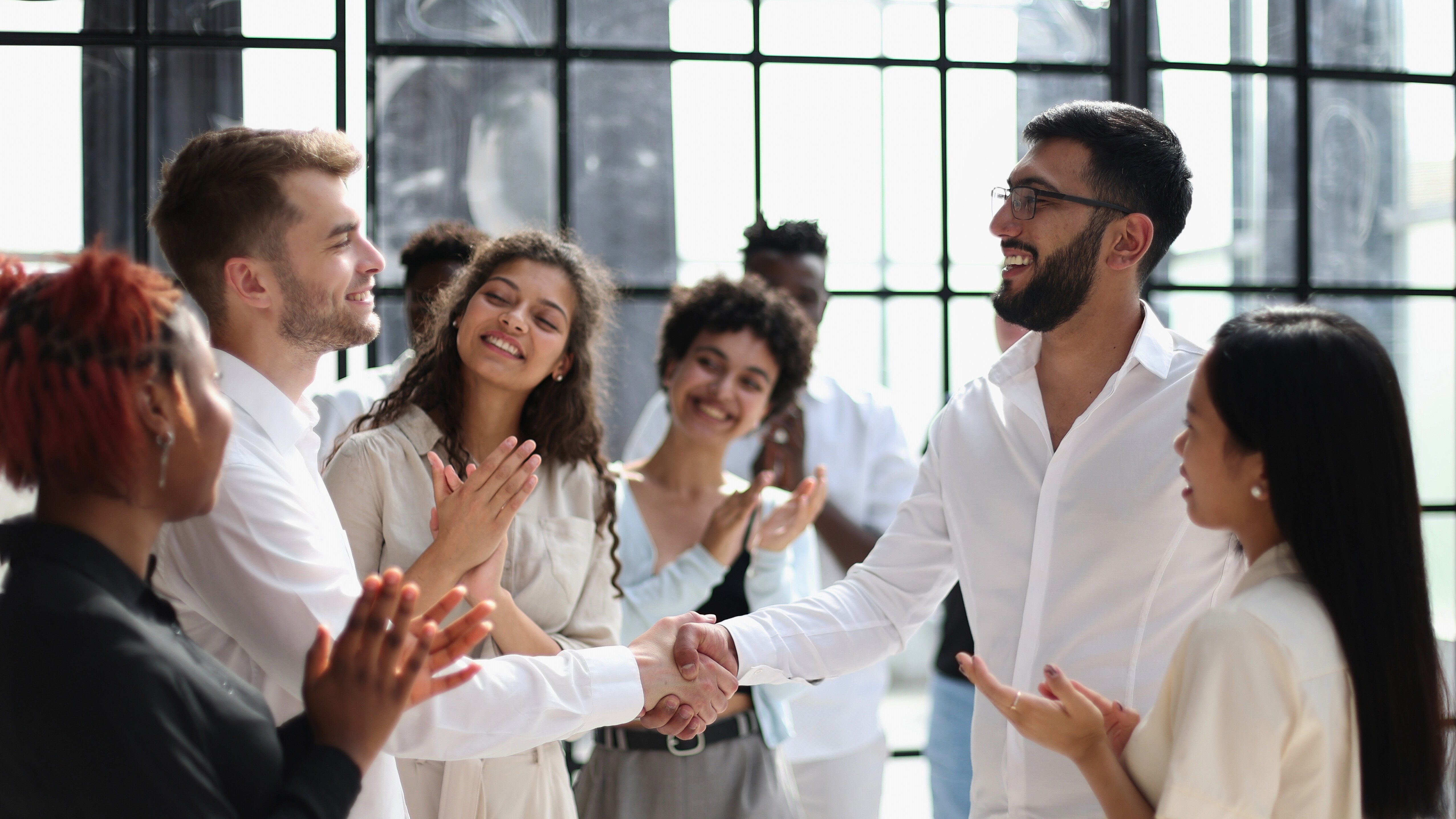 People clapping at two people shaking hands