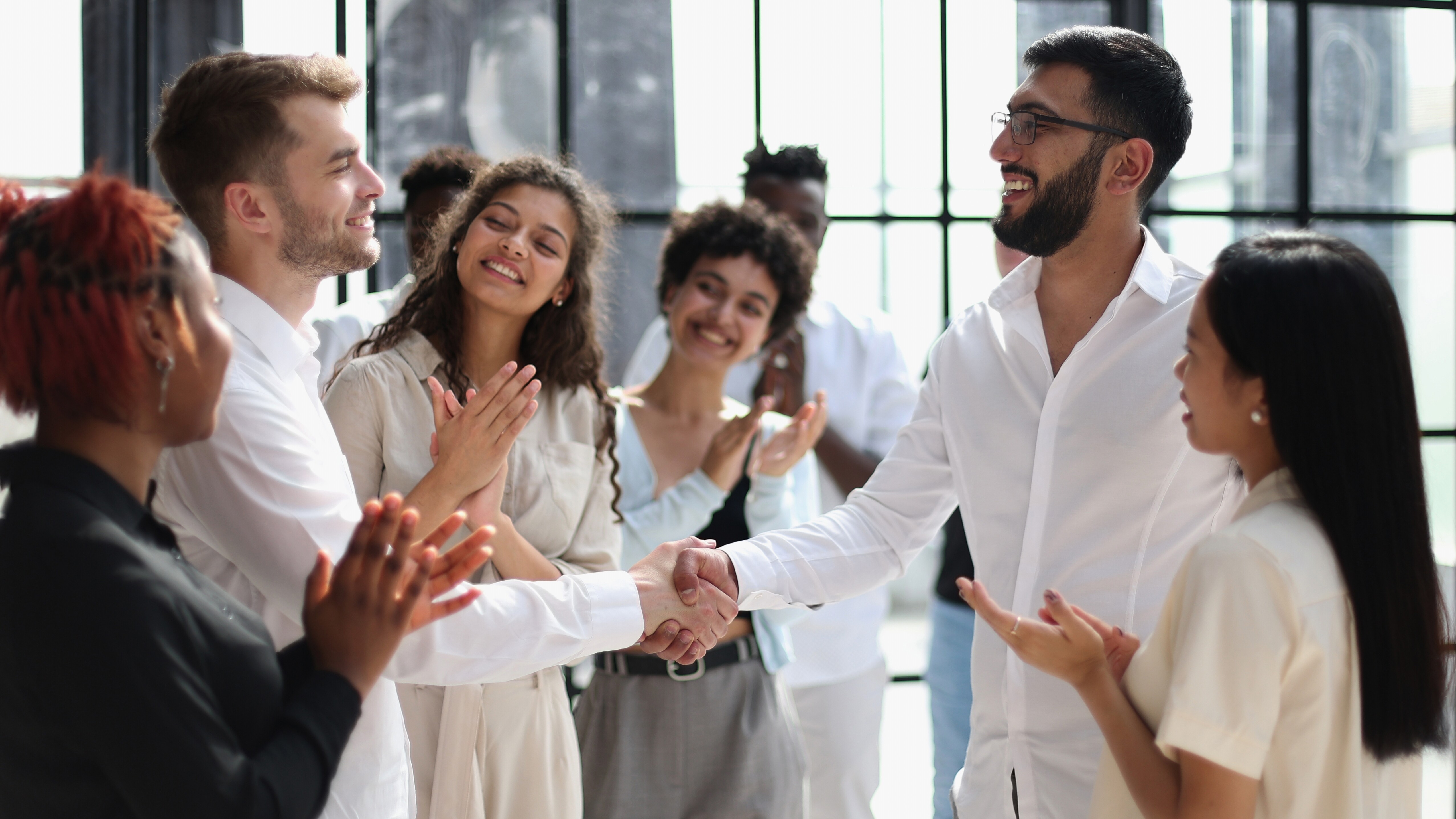 People clapping at two people shaking hands