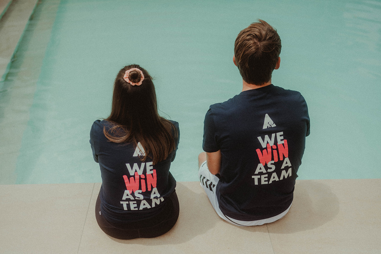 2 seated people from behind with "We win as a team" on the T-shirt © Alissa Lüpke - www.alissa.luepke.us