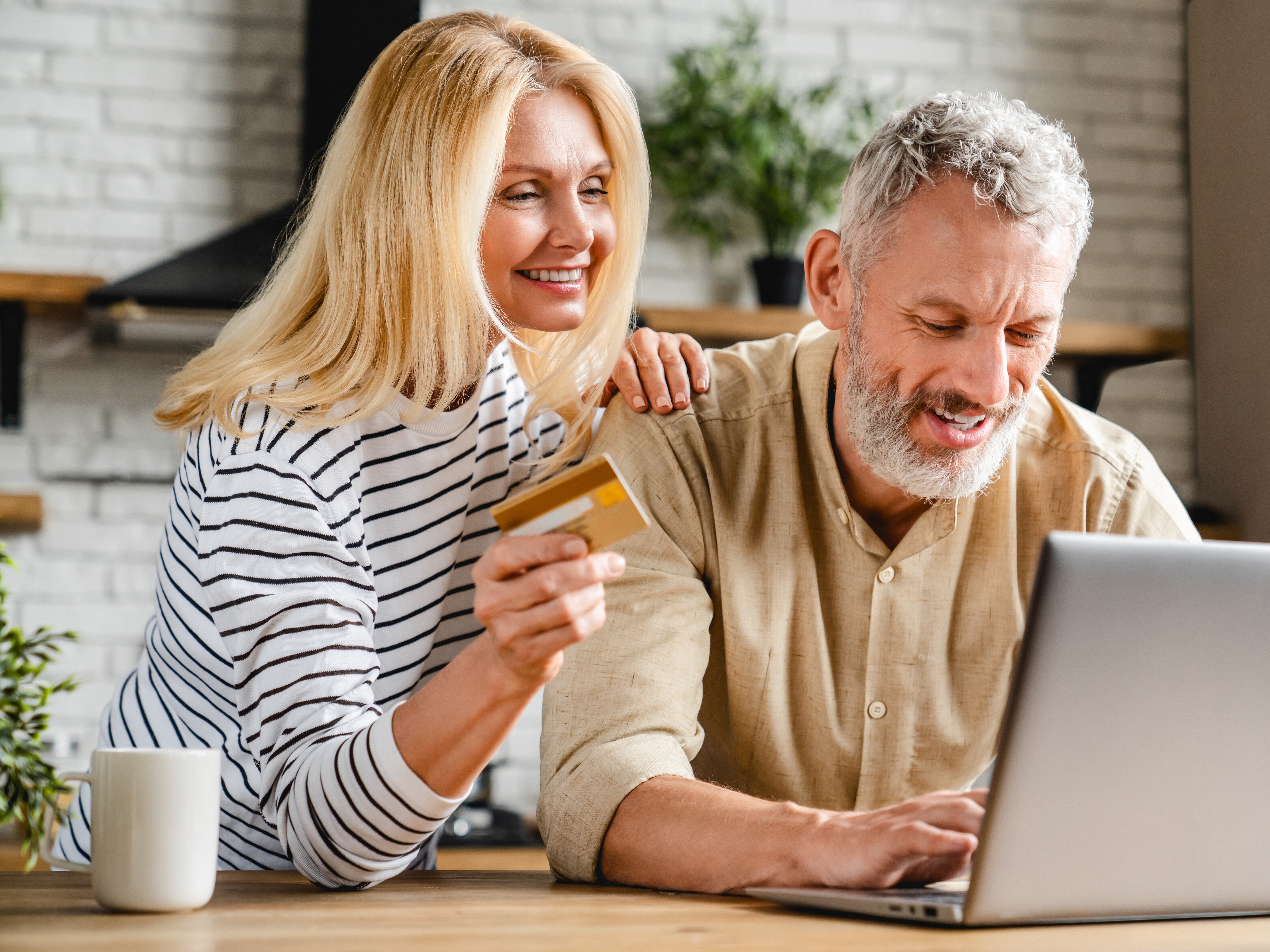 Young woman helping elder man at a laptop