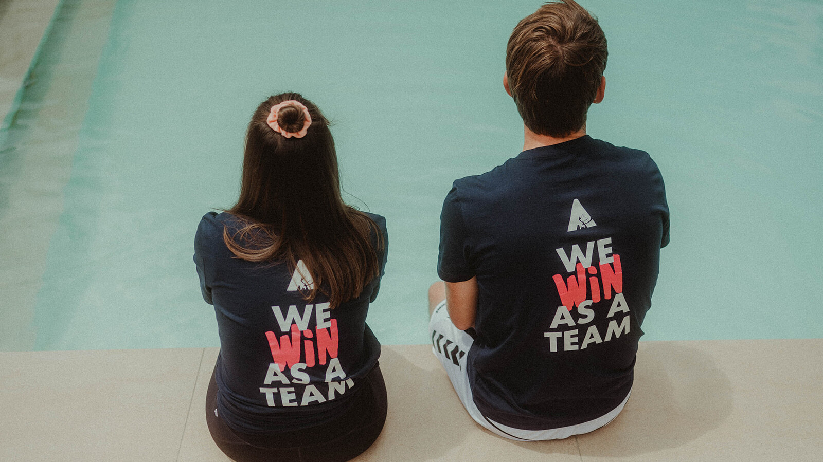 2 seated people from behind with "We win as a team" on the T-shirt © Alissa Lüpke - www.alissa.luepke.us