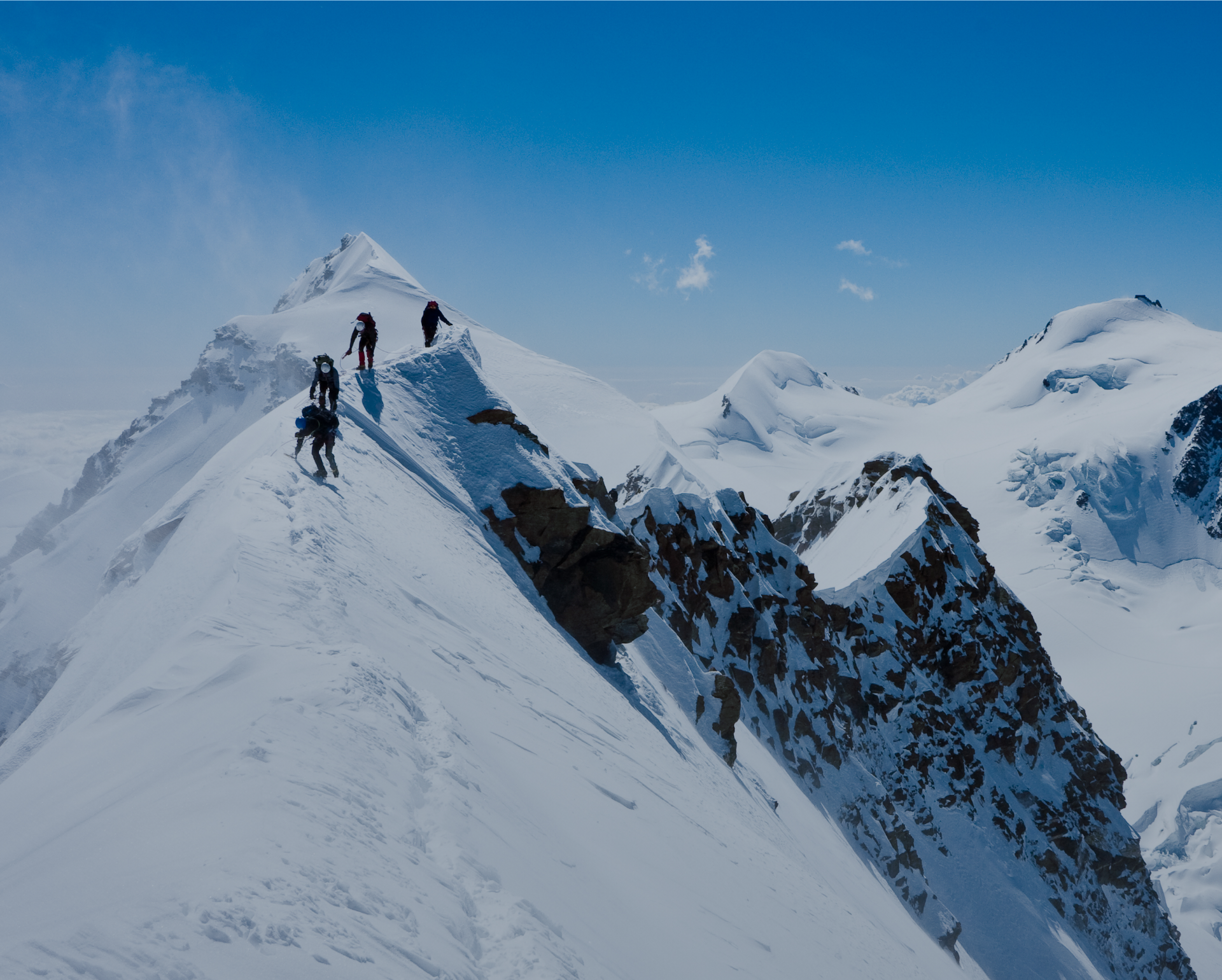 AlphaPet Vision Logo über einem verschneiten Berggipfel mit 4 Kletterern, welche diesen erreichen