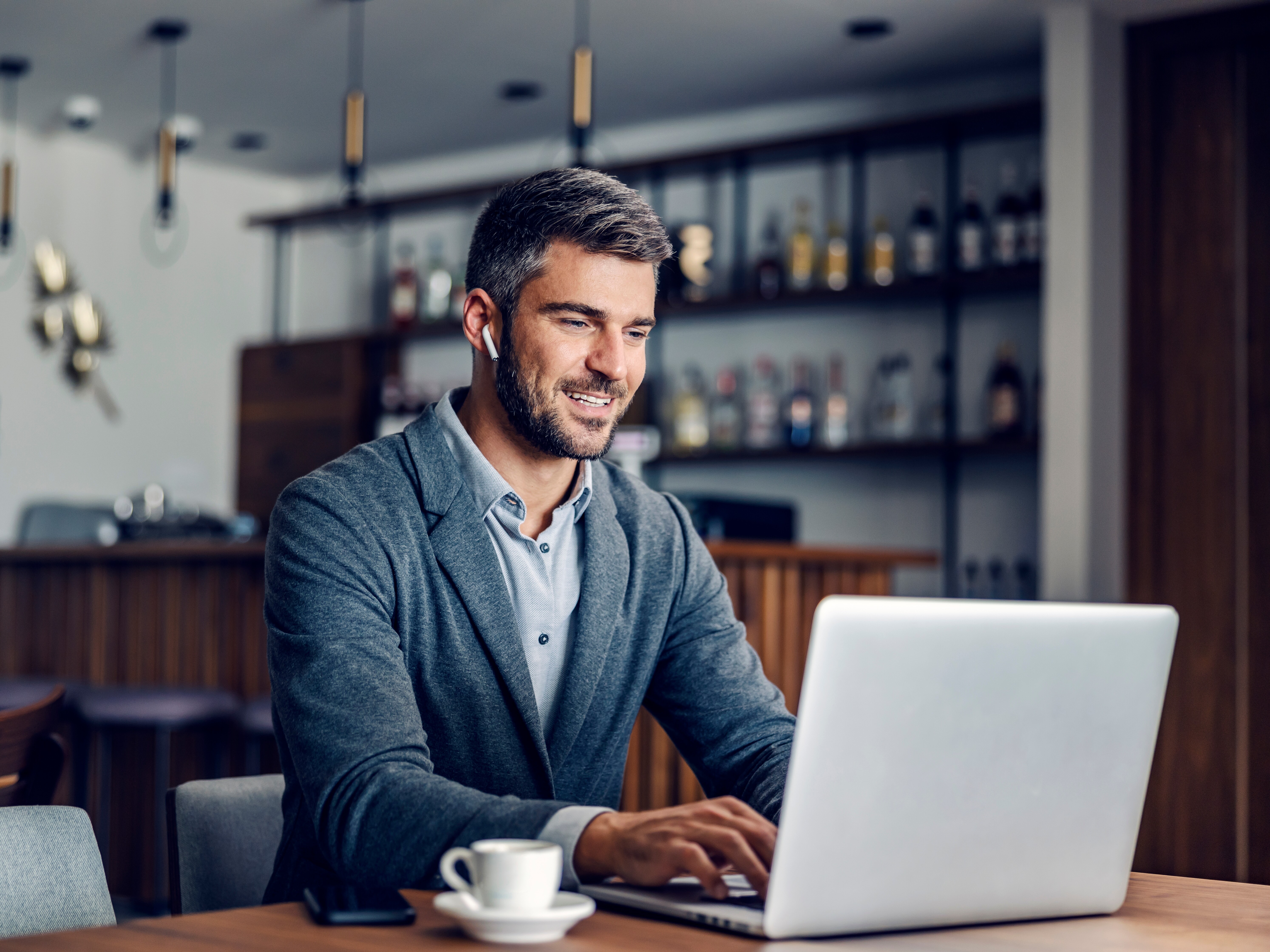 Mann sitzt mit einem Kaffee am Laptop