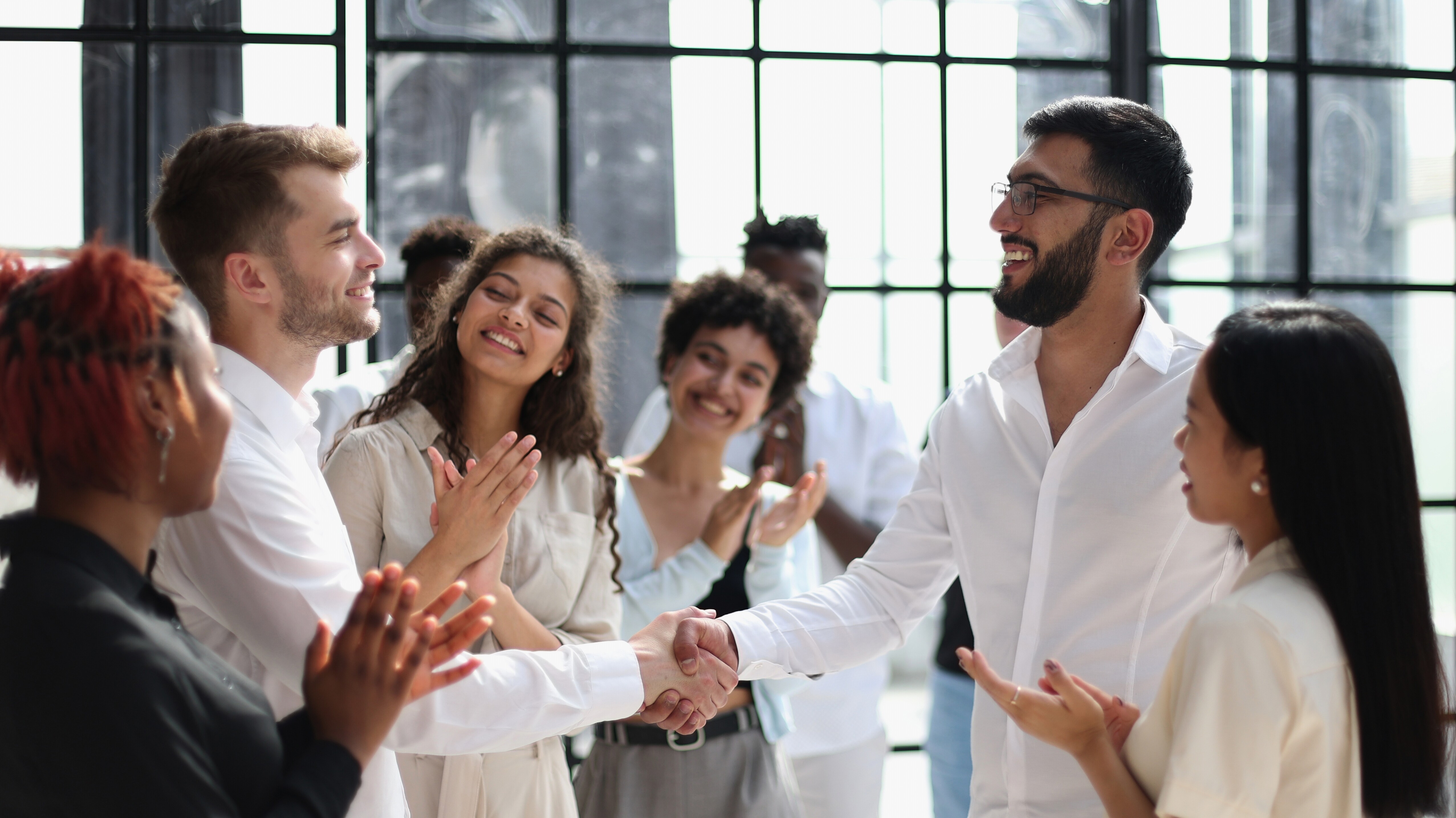 People clapping at two people shaking hands